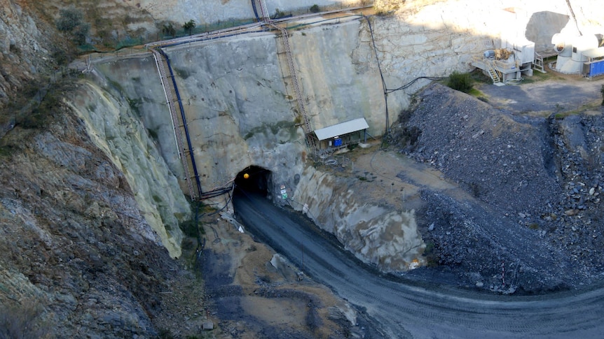 A road leads into the mouth of a cave cut into the side of the open cut mine