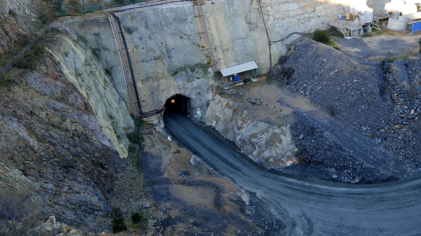 A road leads into the mouth of a cave cut into the side of the open cut mine