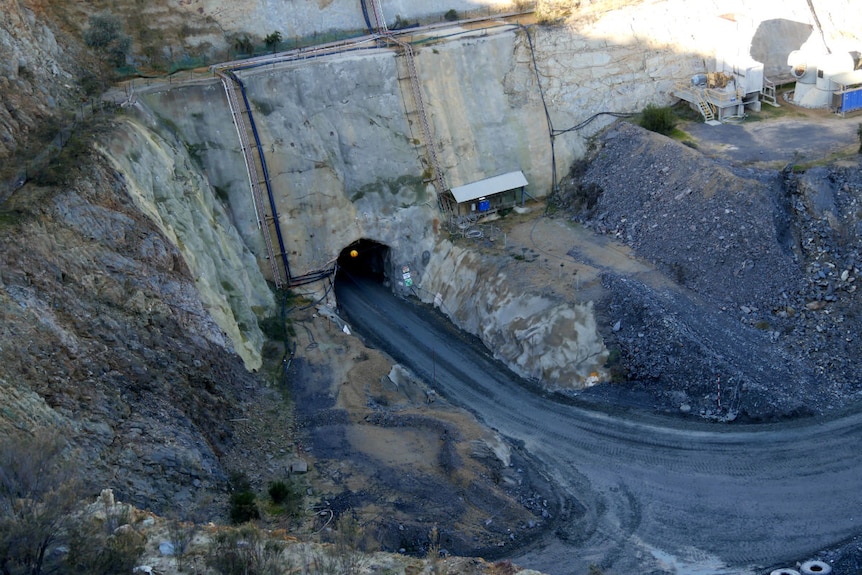A road leads into the mouth of a cave cut into the side of the open cut mine