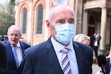A man wearing a suit and tie and a face mask