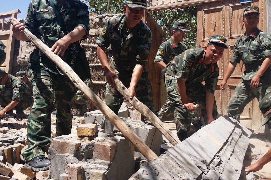 Rescuers help villagers dismantle damaged walls after an earthquake in China's north-east Xinjiang region