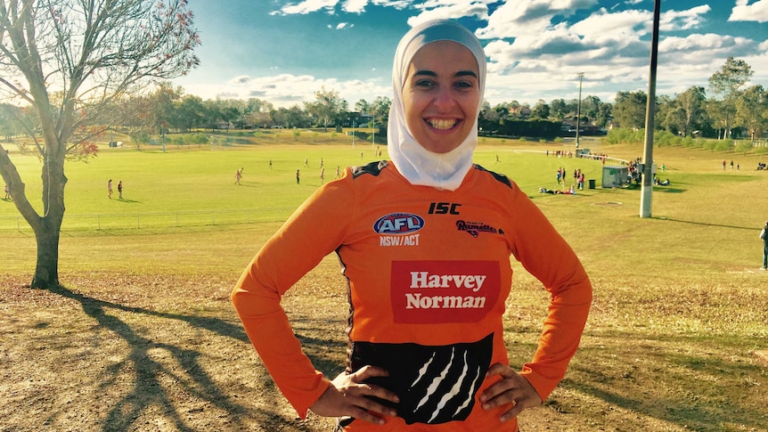 Amna smiling in footy top with hands on hips