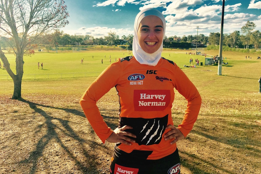 Amna smiling in footy top with hands on hips