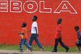Children walk past a slogan painted in Monrovia