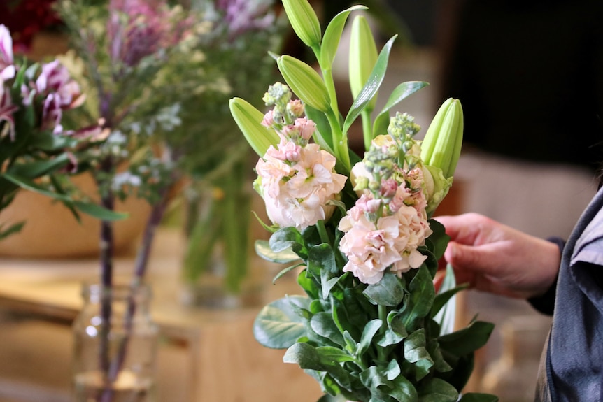 A close up of a woman's hand arranging a bunch of flowers.