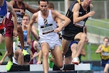 Athletes jump over the steeplechase water jump