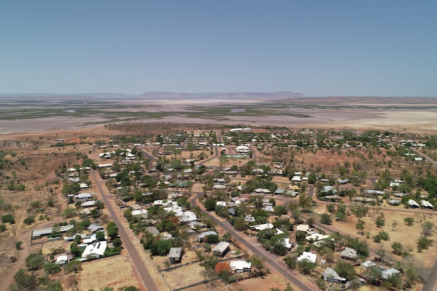 aerial of outback town with salt pans and ranges in the distance