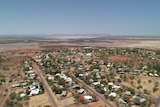 Aerial of outback town with salt pans and ranges in the distance