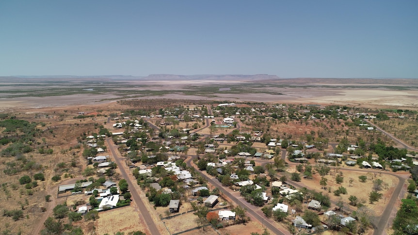 Aerial of outback town with salt pans and ranges in the distance