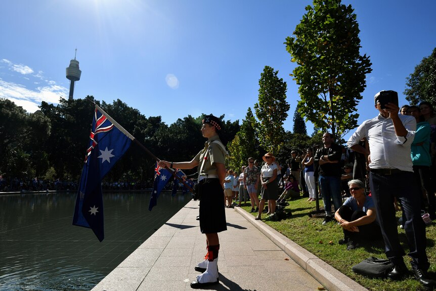 man in uniform holds a flag over a body of water