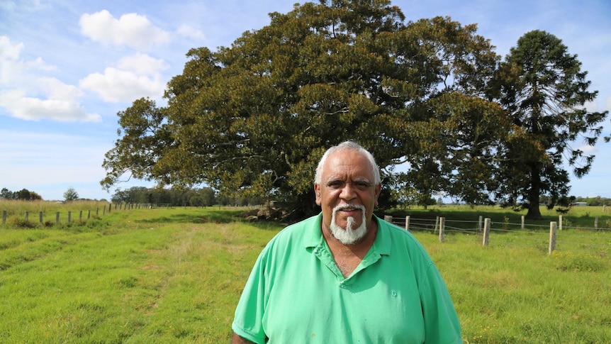 Uncle Richard Campbell stands in front of a large tree, smiling.