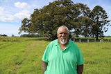 Uncle Richard Campbell stands in front of a large tree, smiling.