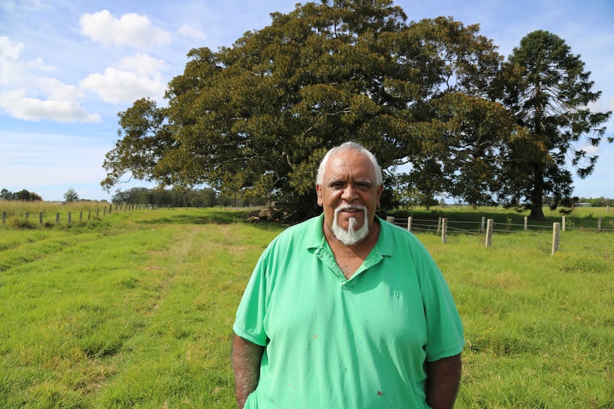 Uncle Richard Campbell stands in front of a large tree, smiling.