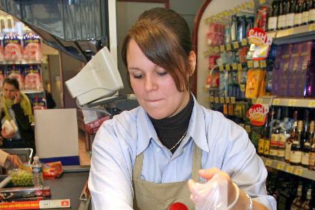 Young worker at a supermarket checkout.