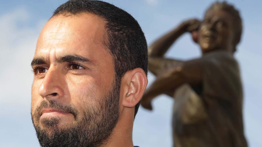 Leg-spinner Fawad Ahmed poses for a picture in front of a statue of Shane Warne at the MCG.