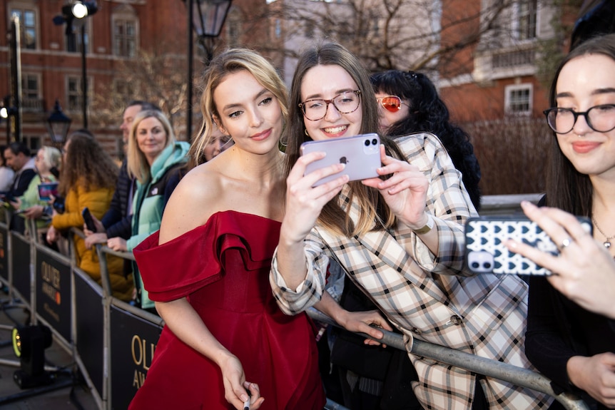 Jodie Comer poses with a fan for a selfie.