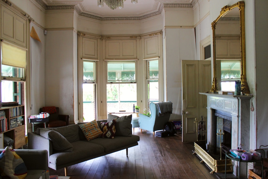 An elegant white room with sash windows, with a gilt mirror and white marbleplace
