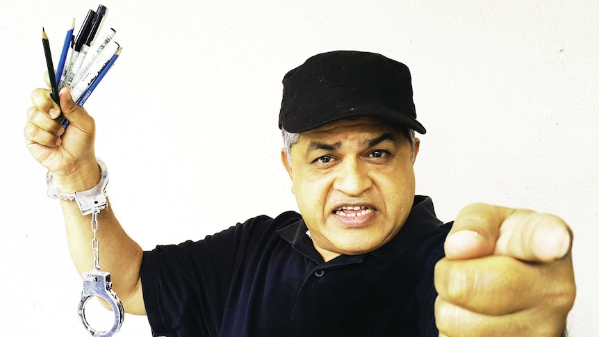 Zunar holding pens aloft, with one wrist handcuffed