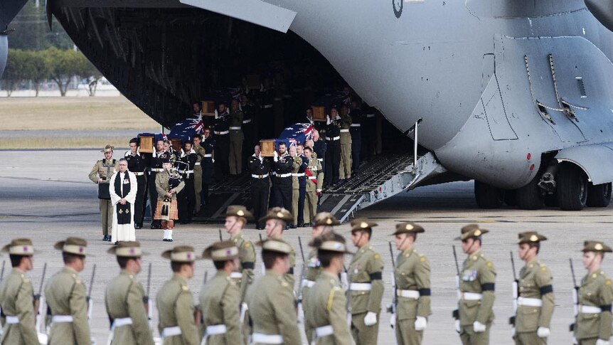 Australian Defence Force personnel carry coffins down the ramp of a C-17 Globemaster III.