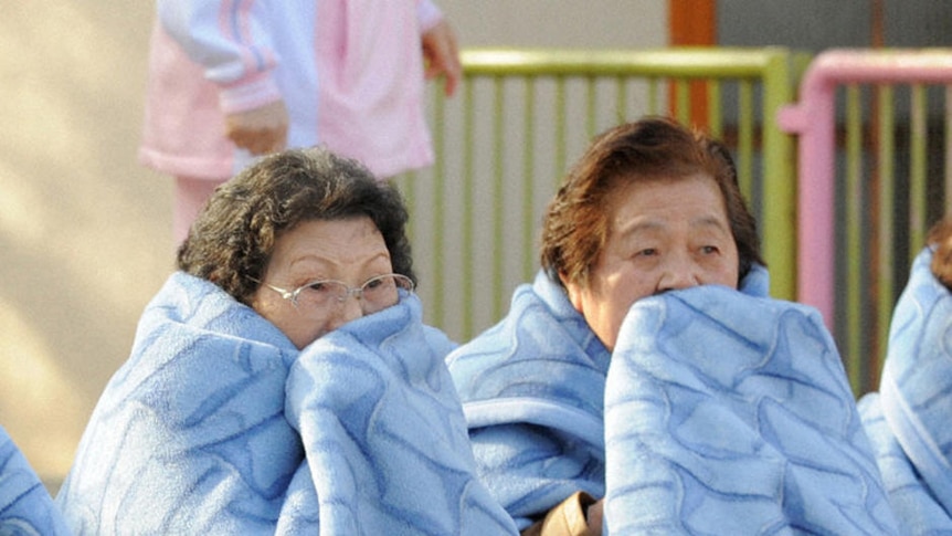 Women wait on the street after evacuating a building following the earthquake.