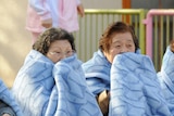 Women wait on the street after evacuating a building following an earthquake in Tokyo