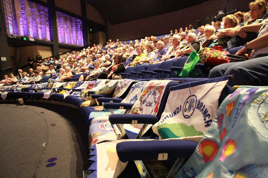 A large theatre filled with QCWA members and quilted branch banners