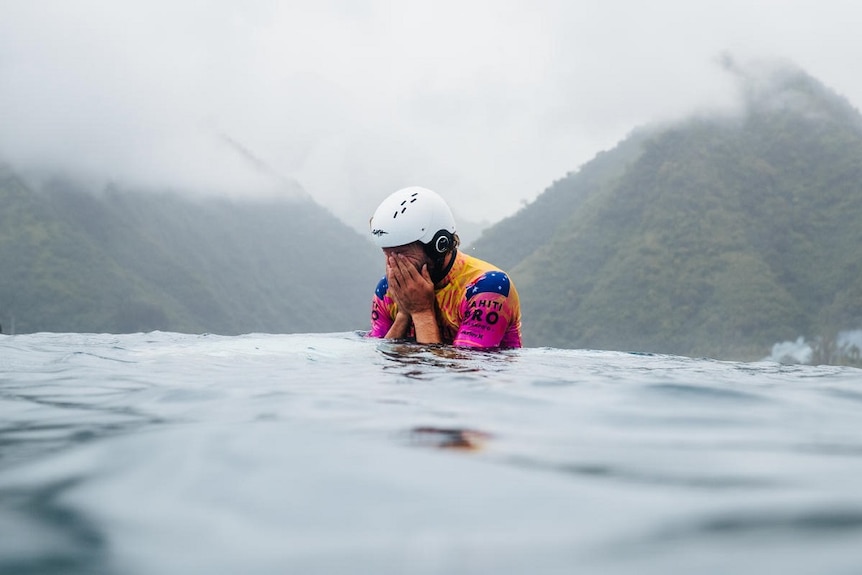 Australian surfer Owen Wright covers his face as he is overcome by emotion after winning the Tahitit Pro while wearing a safety