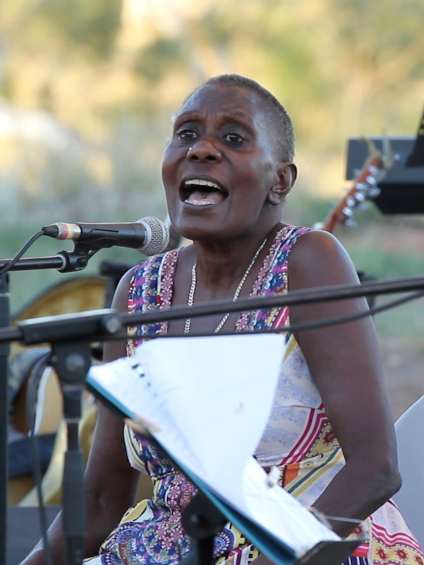 A woman singing and a man playing music.