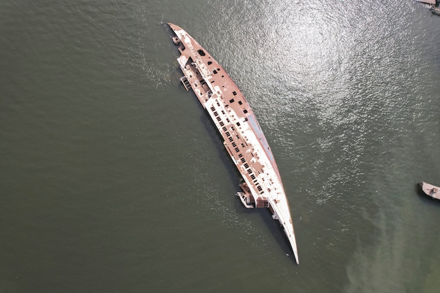 Birds eye view of a rusting yacht capsized in water