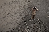 A boy stands in the mud