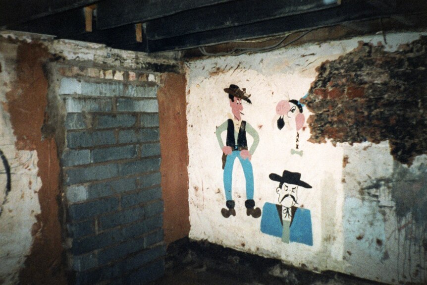 A cowboy painted on the brick wall of a basement 