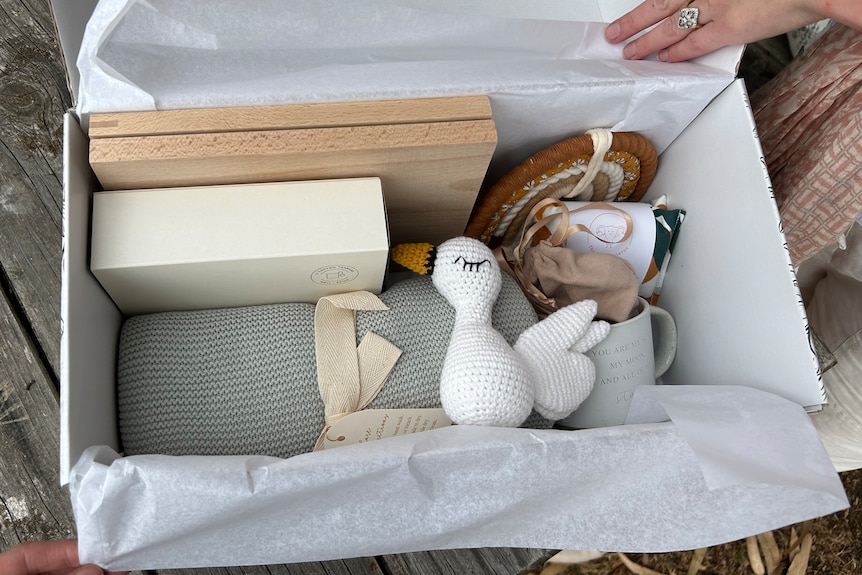 A collection of keepsake items like a duck, blanket and photoframe wrapped in a box.