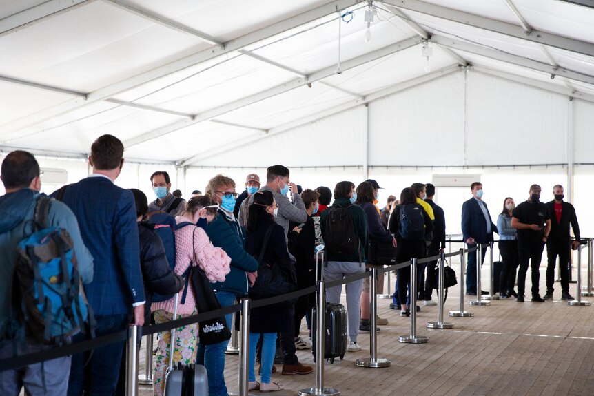 A queue of people in a tent with suitcases.