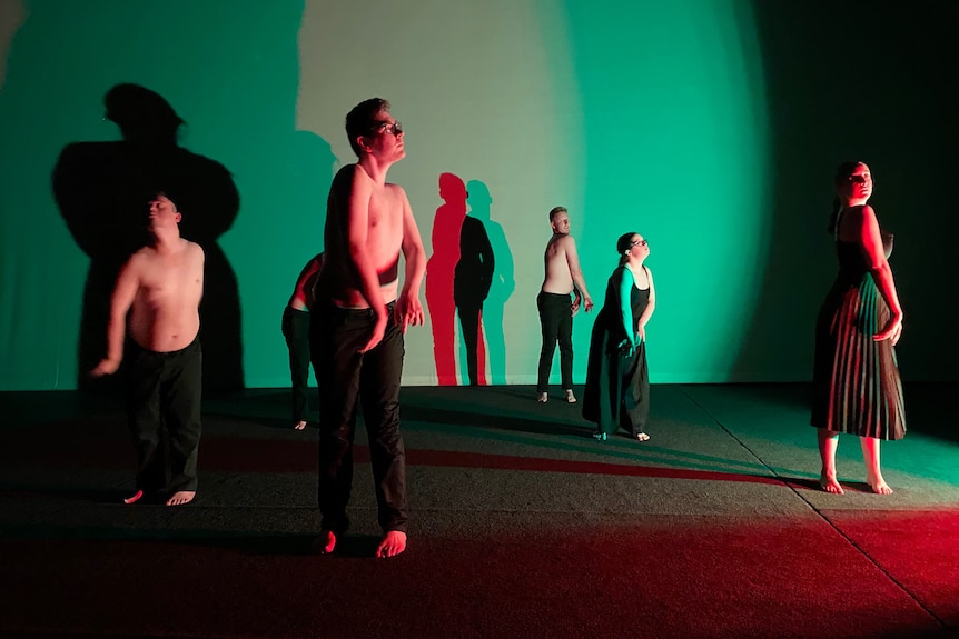 Six dancers dancing, they are lit in a green light