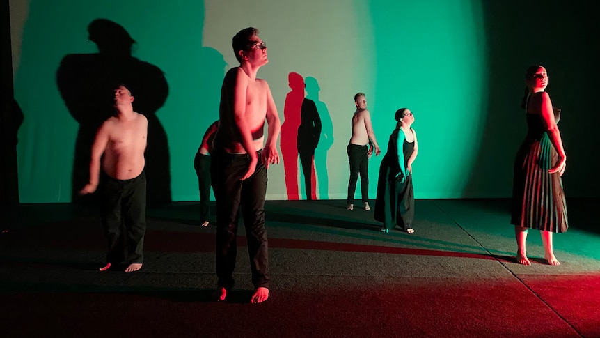 Six dancers dancing, they are lit in a green light