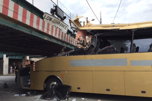 The wreckage of a bus wedged under a bridge.