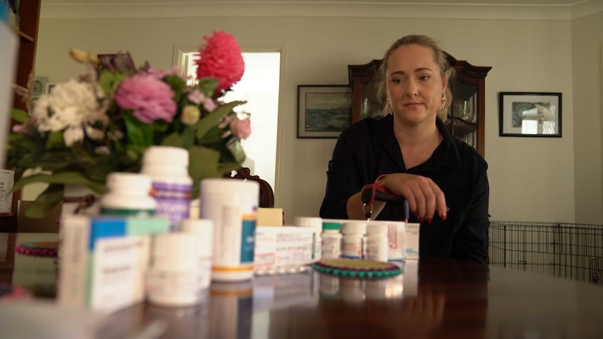 Mandy Hunwick looks at her medication on a dining table.