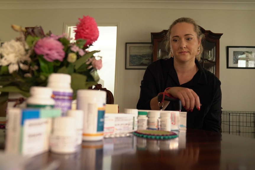 Mandy Hunwick looks at her medication on a dining table.