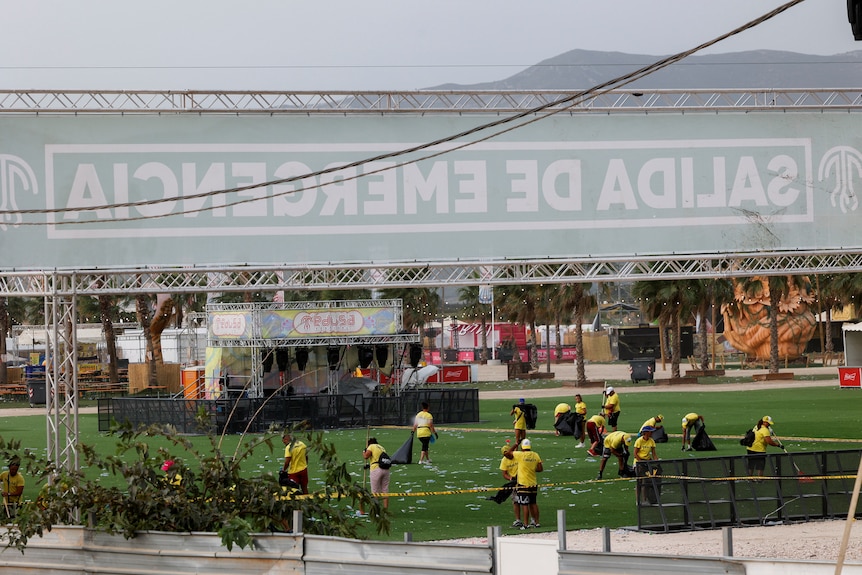 Staff members clean the festival venue after the stage collapsed in high wind. 