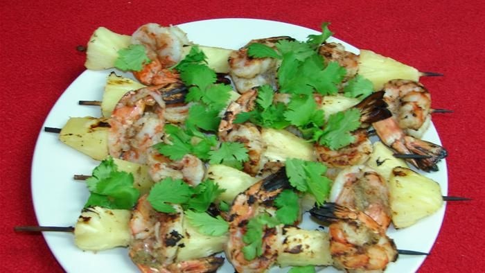 BBQ prawn and pineapple skewers on a plate.