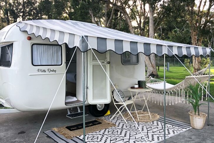 The exterior of a renovated 1964 Sunliner caravan with hammock and awning.