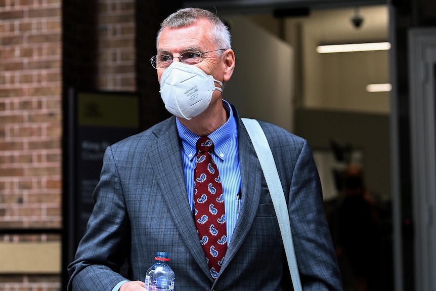 a man wearing a face mask leaving a court room