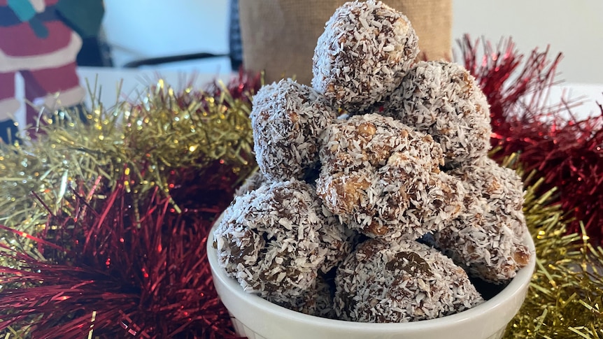 A bowl of rum balls surrounded by tinsel 