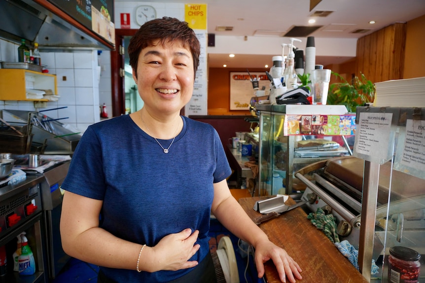 Woman behind counter in sandwich shop smiles