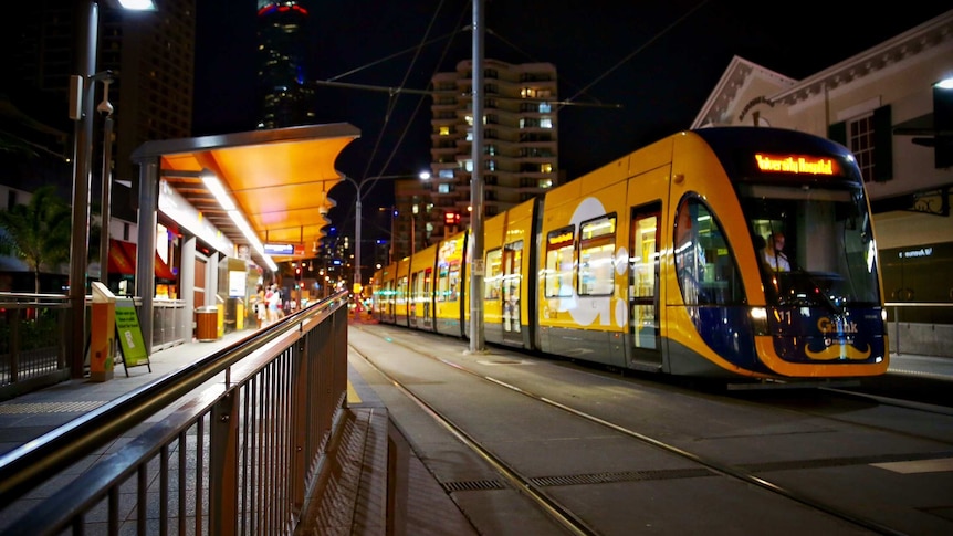 Night time photo of light rail stopped at lit up station 