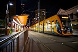A tram pulls int a station at night.