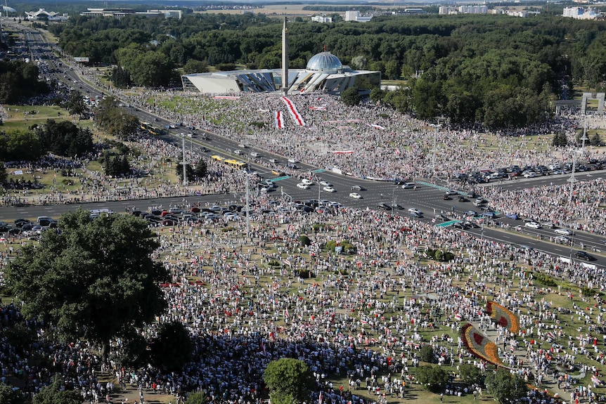 An aerial shot shows a large crowd sprawled across an open area near a major road intersection.
