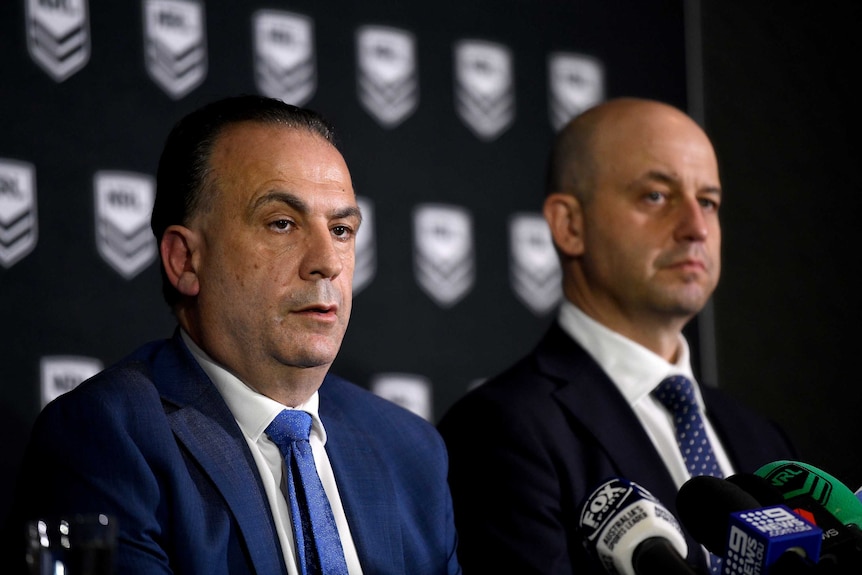 Two men sit at a table during an NRL press conference.