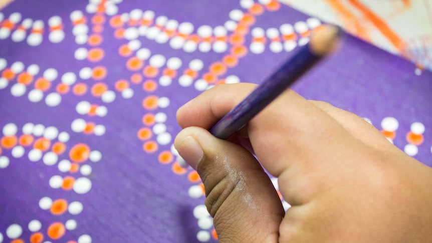 A hand paints a dot pattern.