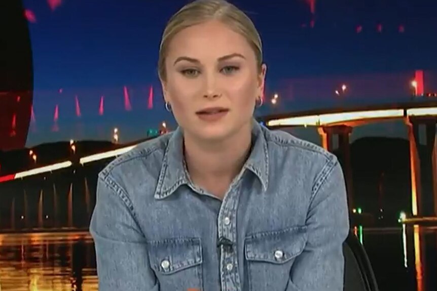 A woman with blond hair wears a denim blouse.